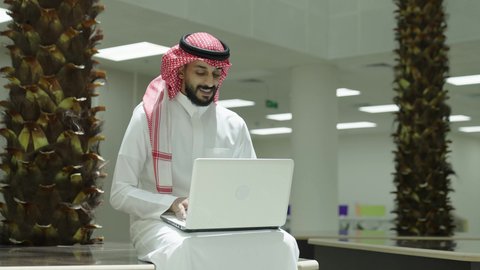 إجراء اختبارات وأبحاث علمية عبر الانترنت، دمج التعلم مع التكنولوجيا، التعليم العالي في الجامعات والكليات الأكاديمية، رجل عربي خليجي سعودي يرتدي الزي التقليدي يقوم باستخدام الحاسوب داخل الجامعة، جودة التعليم الجامعي في المملكة