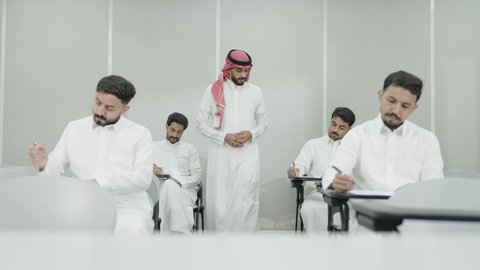 الدراسة والاجتهاد من اجل التفوق، ورش عمل ودورات تدريبية، التعليم الجامعي في المملكة العربية السعودية, دكتور جامعي عربي خليجي سعودي يرتدي الشماغ والثوب التقليدي يقوم بمراقبة الطلاب،  طلاب جامعيون يقومون بتقديم الاختبارات، تدوين وكتابة الملاحظات والتقارير