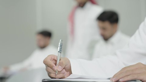 تدوين وكتابة الملاحظات والتقارير، التعليم الجامعي في المملكة العربية السعودية, الدراسة والاجتهاد من اجل التفوق، ورش عمل ودورات تدريبية، دكتور جامعي عربي خليجي سعودي يرتدي الشماغ والثوب التقليدي يقوم بالاجابة عن سؤال الطالب،  طلاب جامعيون يقومون بتقديم الاختبارات