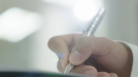 التعليم الجامعي في المملكة العربية السعودية, ورش عمل ودورات تدريبية، التفكير في الإجابة الصحيحة، الدراسة والاجتهاد من اجل التفوق، تصوير مقرب ليد طالب جامعي عربي خليجي سعودي يرتدي الثوب التقليدي يقوم بتقديم الاختبارات، تدوين وكتابة الملاحظات والتقارير