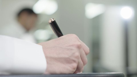 التعليم الجامعي في المملكة العربية السعودية, ورش عمل ودورات تدريبية، التفكير في الإجابة الصحيحة، الدراسة والاجتهاد من اجل التفوق، تصوير مقرب ليد طالب جامعي عربي خليجي سعودي يرتدي الثوب التقليدي يقوم بتقديم الاختبارات، تدوين وكتابة الملاحظات والتقارير