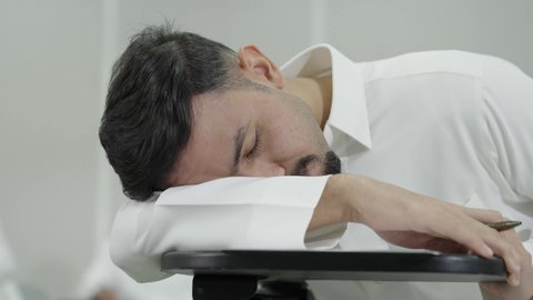 Fatigue and stress during daily lectures, higher education in the Kingdom of Saudi Arabia, the pursuit of excellence and success, an Arab Gulf Saudi university student wearing traditional attire sleeping in the classroom, difficulty waking up early.