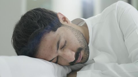 The quality of higher education in the Kingdom of Saudi Arabia, the difficulty of waking up early, the pursuit of excellence and success, the fatigue and exhaustion during daily lectures, an Arab Gulf Saudi university student wearing traditional attire sleeping at the study desk.