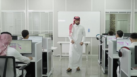 دمج التعلم مع التكنولوجيا، التعليم العالي في الجامعات والكليات الأكاديمية, اختبارات وكتابة التقارير والأبحاث العلمية، أستاذ جامعي عربي خليجي سعودي يرتدي الثوب التقليدي والشماغ يتجول ويقوم بشرح المعلومات على الطلاب، جودة التعليم الجامعي في المملكة العربية السعودية