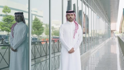 مفهوم الأناقة والوسامة، رجل عربي خليجي سعودي يرتدي الثوب والشماغ التقليدي ينظر إلى الكاميرا بإيماءات السرور، الاناقة والاهتمام بالمظهر الخارجي، الوقوف بأيدي متقاطعة