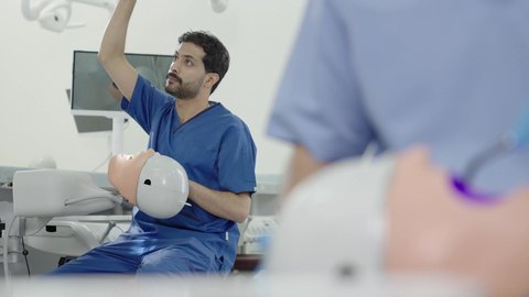 استخدام معدات وأدوات طب الأسنان، الأساليب العلاجية المتبعة للعناية بالفم، معالجة التسوس وتركيب الحشوات، مجموعة من الطلاب الجامعيين بكلية الأسنان يرتدون القفازات يقومون بفحص الأسنان على مجسم