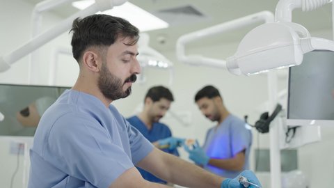 Treatment of cavities and placement of fillings, use of dental equipment and tools, therapeutic methods followed for oral care, a group of university students in the dental college wearing gloves examining teeth on a model.