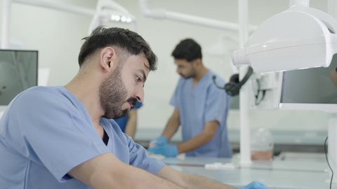 الأساليب العلاجية المتبعة للعناية بالفم، استخدام معدات وأدوات طب الأسنان،معالجة التسوس وتركيب الحشوات، مجموعة من الطلاب الجامعيين بكلية الأسنان يرتدون القفازات يقومون بفحص الأسنان على مجسم