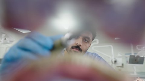 استخدام معدات وأدوات طب الأسنان، تصوير مقرب لطالب جامعي بكلية الأسنان يرتدي القفازات يقوم بفحص مجسم طاقم أسنان، مفهوم التدريب العملي، الأساليب العلاجية المتبعة للعناية بالفم، معالجة التسوس وتركيب الحشوات