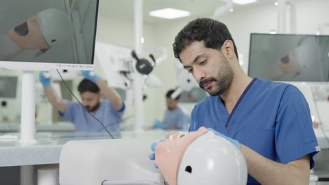 الأساليب العلاجية المتبعة للعناية بالفم ،المعدات والادوات اللازمة لإجراء الفحوصات، معالجة النخر والتسوس,تصوير مقرب لطالب جامعي بكلية الأسنان يرتدي القفازات يقوم بفحص مجسم طاقم أسنان، مفهوم التدريب العملي