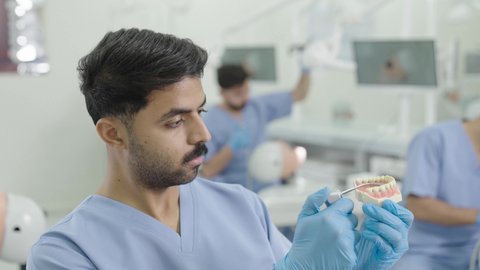 المعدات والادوات اللازمة لإجراء الفحوصات، معالجة النخر والتسوس,تصوير مقرب لطالب جامعي بكلية الأسنان يرتدي القفازات يقوم بحقن البنج الموضعي باستخدام الإبرة على مجسم طاقم اسنان ، مفهوم التدريب العملي، الأساليب العلاجية المتبعة للعناية بالفم