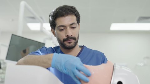 معالجة النخر والتسوس,المعدات والادوات اللازمة لإجراء الفحوصات، تصوير مقرب لطالب جامعي بكلية الأسنان يرتدي القفازات يقوم بفحص مجسم طاقم أسنان، مفهوم التدريب العملي، الأساليب العلاجية المتبعة للعناية بالفم