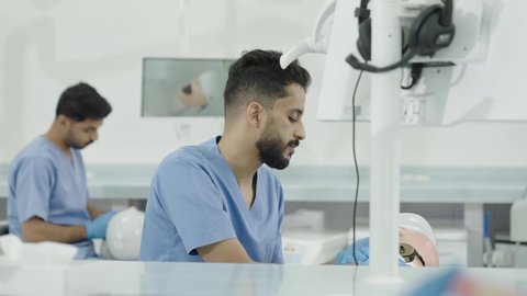 استخدام معدات وأدوات طب الأسنان، الأساليب العلاجية المتبعة للعناية بالفم، معالجة التسوس وتركيب الحشوات، مجموعة من الطلاب الجامعيين بكلية الأسنان يرتدون القفازات يقومون بفحص الأسنان على مجسم