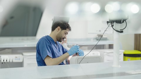 تصوير مقرب لطالب جامعي سعودي بكلية الأسنان يرتدي القفازات يقوم بفحص مجسم طاقم أسنان، مفهوم التدريب العملي، استخدام معدات وأدوات طب الأسنان، الأساليب العلاجية المتبعة للعناية بالفم، معالجة التسوس وتركيب الحشوات 50 وسم