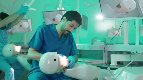 ، مجموعة من الطلاب الجامعيين بكلية الأسنان يرتدون القفازات يقومون بفحص الأسنان على مجسم، استخدام معدات وأدوات طب الأسنان، الأساليب العلاجية المتبعة للعناية بالفم، معالجة التسوس وتركيب الحشوات