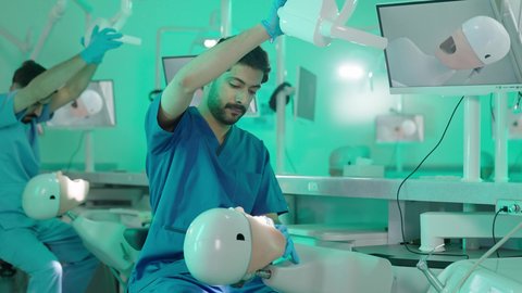 Treatment of cavities and placement of fillings, use of dental equipment and tools, therapeutic methods followed for oral care, a group of university students in the dental college wearing gloves examining teeth on a model.