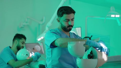 معالجة التسوس وتركيب الحشوات، استخدام معدات وأدوات طب الأسنان، الأساليب العلاجية المتبعة للعناية بالفم، مجموعة من الطلاب الجامعيين بكلية الأسنان يرتدون القفازات يقومون بفحص الأسنان على مجسم