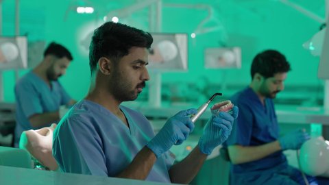 مجموعة من الطلاب الجامعيين بكلية الأسنان يرتدون القفازات يقومون بفحص الأسنان على مجسم، استخدام معدات وأدوات طب الأسنان، الأساليب العلاجية المتبعة للعناية بالفم، معالجة التسوس وتركيب الحشوات
