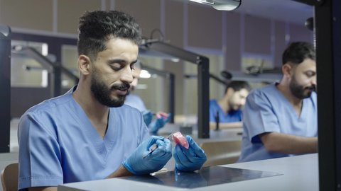 معالجة التسوس وتركيب الحشوات، استخدام معدات وأدوات طب الأسنان، الأساليب العلاجية المتبعة للعناية بالفم، مجموعة من الطلاب الجامعيين بكلية الأسنان يرتدون القفازات يقومون بفحص الأسنان على مجسم