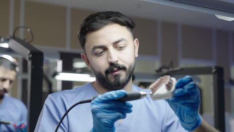 استخدام معدات وأدوات طب الأسنان، الأساليب العلاجية المتبعة للعناية بالفم، معالجة التسوس وتركيب الحشوات، مجموعة من الطلاب الجامعيين بكلية الأسنان يرتدون القفازات يقومون بفحص الأسنان على مجسم