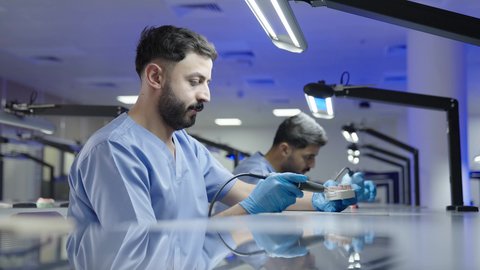 مفهوم العناية بصحة الفم، التعليم الجامعي فى المملكه العربيه السعوديه ، معالجة التسوس وتركيب الحشوات،استخدام معدات وأدوات طب الأسنان، الأساليب العلاجية المتبعة للعناية بالفم، مجموعة من الطلاب الجامعيين السعوديين بكلية الأسنان يرتدون القفازات يقومون بنحت طاقم أسنان