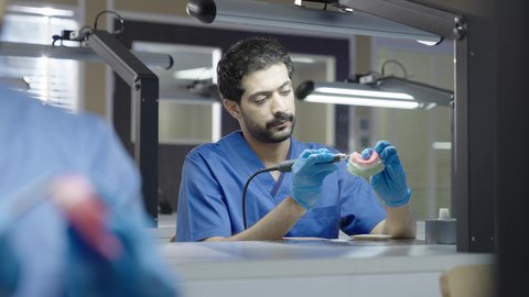 معالجة التسوس وتركيب الحشوات،استخدام معدات وأدوات طب الأسنان، الأساليب العلاجية المتبعة للعناية بالفم، التعليم الجامعي فى المملكه العربيه السعوديه ، مجموعة من الطلاب الجامعيين السعوديين بكلية الأسنان يرتدون القفازات يقومون بنحت طاقم أسنان