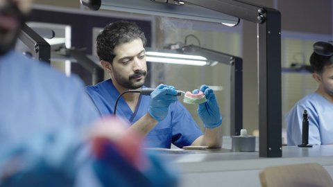 التعليم الجامعي فى المملكه العربيه السعوديه ، معالجة التسوس وتركيب الحشوات،استخدام معدات وأدوات طب الأسنان، الأساليب العلاجية المتبعة للعناية بالفم، مجموعة من الطلاب الجامعيين السعوديين بكلية الأسنان يرتدون القفازات يقومون بنحت طاقم أسنان