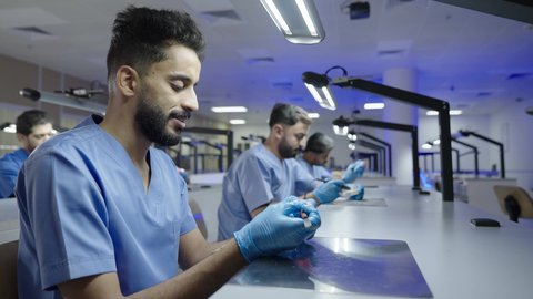 الأساليب العلاجية المتبعة للعناية بالفم، التعليم الجامعي فى المملكه العربيه السعوديه ، معالجة التسوس وتركيب الحشوات،استخدام معدات وأدوات طب الأسنان،مجموعة من الطلاب الجامعيين السعوديين بكلية الأسنان يرتدون القفازات يقومون بنحت طاقم أسنان