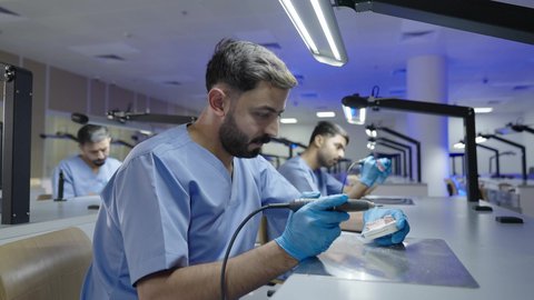 مجموعة من الطلاب الجامعيين السعوديين بكلية الأسنان يرتدون القفازات يقومون بنحت طاقم أسنان، التعليم الجامعي فى المملكه العربيه السعوديه ، معالجة التسوس وتركيب الحشوات،استخدام معدات وأدوات طب الأسنان، الأساليب العلاجية المتبعة للعناية بالفم