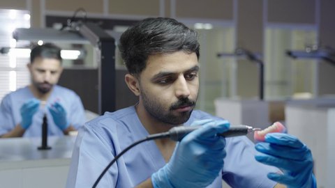 مفهوم العناية بصحة الفم، التعليم الجامعي فى المملكه العربيه السعوديه ، معالجة التسوس وتركيب الحشوات،استخدام معدات وأدوات طب الأسنان، الأساليب العلاجية المتبعة للعناية بالفم، مجموعة من الطلاب الجامعيين السعوديين بكلية الأسنان يرتدون القفازات يقومون بنحت طاقم أسنان