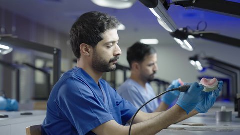 معالجة التسوس وتركيب الحشوات،استخدام معدات وأدوات طب الأسنان، الأساليب العلاجية المتبعة للعناية بالفم، التعليم الجامعي فى المملكه العربيه السعوديه ، مجموعة من الطلاب الجامعيين السعوديين بكلية الأسنان يرتدون القفازات يقومون بنحت طاقم أسنان