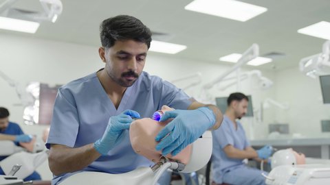 استخدام معدات وأدوات طب الأسنان، معالجة التسوس وتركيب الحشوات،الأساليب العلاجية المتبعة للعناية بالفم، مجموعة من الطلاب الجامعيين السعوديين بكلية الأسنان يرتدون القفازات يقومون بفحص الأسنان على مجسم