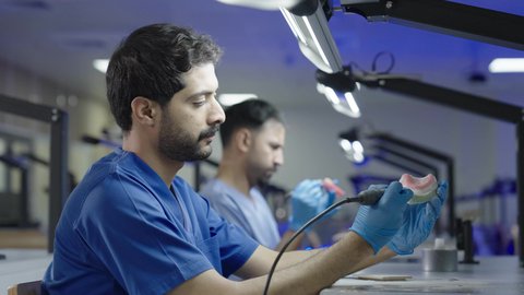 Higher education in the Kingdom of Saudi Arabia, treating cavities and placing fillings, using dental equipment and tools, a group of Saudi university students in the College of Dentistry wearing gloves are sculpting a set of dentures.