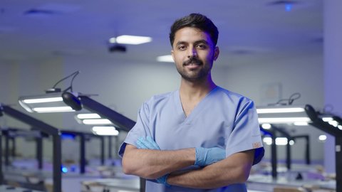 طالب جامعي عربي سعودي بكلية الاسنان يقف بايدي متقاطعه  ، مفهوم العنايه بصحة الفم، التعليم الجامعي فى المملكه العربيه السعوديه ، النظر الى الكاميرا بايماءات السعاده والثقه بالنفس ، التدريب العملي  فى السعودية