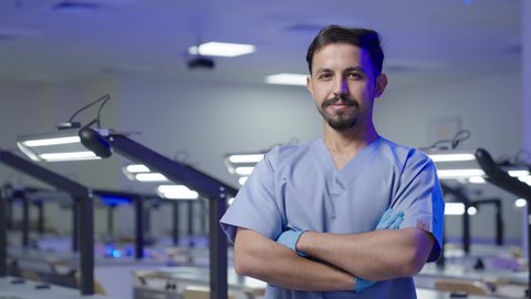 التدريب العملي  فى السعودية، النظر الى الكاميرا بايماءات السعاده والثقه بالنفس ، التعليم الجامعي فى المملكه العربيه السعوديه ،طالب جامعي عربي سعودي بكلية الاسنان يقف بايدي متقاطعه  ، مفهوم العنايه بصحة الفم