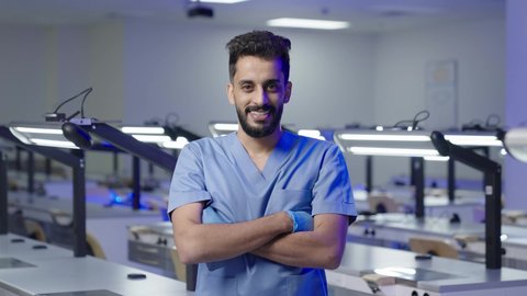 مفهوم العنايه بصحة الفم، التعليم الجامعي فى المملكه العربيه السعوديه ، النظر الى الكاميرا بايماءات السعاده والثقه بالنفس ، طالب جامعي عربي سعودي بكلية الاسنان يقف بايدي متقاطعه  ،  التدريب العملي  فى السعودية