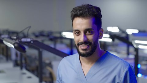 A Saudi Arabian Arab university student in the dental college stands with crossed arms, the concept of oral health care, higher education in the Kingdom of Saudi Arabia, looking at the camera with gestures of happiness and self-confidence, practical training in Saudi Arabia.