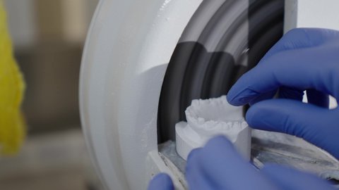 الأساليب العلاجية المتبعة للعناية بالفم، التعليم الجامعي فى المملكه العربيه السعوديه ، معالجة التسوس وتركيب الحشوات،استخدام معدات وأدوات طب الأسنان، تصوير مقرب ليد طالب جامعي سعودي بكلية الأسنان يرتدي القفازات يقوم بنحت طاقم أسنان