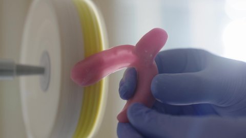 استخدام معدات وأدوات طب الأسنان، التعليم الجامعي فى المملكه العربيه السعوديه ، معالجة التسوس وتركيب الحشوات، الأساليب العلاجية المتبعة للعناية بالفم، تصوير مقرب ليد طالب جامعي سعودي بكلية الأسنان يرتدي القفازات يقوم بنحت طاقم أسنان