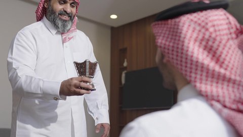 عادات وتقاليد المجتمع السعودي في الأعياد والمناسبات الاسلامية، الاصالة والعراقة والتراث السعودي, عطورات وروائح خليجية مميزة، رجل شايب كبير بالسن عربي خليجي سعودي يرتدي الثوب التقليدي والشماغ يقوم بتبخير نفسه بالمبخرة برفقة ابنه، التبخر والتطيب بخشب العود