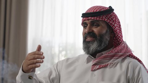 عادات وتقاليد المجتمع السعودي في الأعياد والمناسبات الاسلامية، الاصالة والعراقة والتراث السعودي, عطورات وروائح خليجية مميزة، رجل شايب كبير بالسن عربي خليجي سعودي يرتدي الثوب التقليدي والشماغ يقوم بتبخير نفسه بالمبخرة برفقة ابنه، التبخر والتطيب بخشب العود