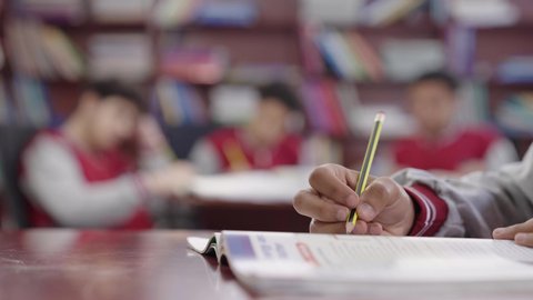 حل الواجبات المدرسية، مراجعة الدروس، الإستعداد للعام الدراسي الجديد، التعليم الدراسي في السعودية ، العودة إلى المدارس، المذاكرة للإختبارات الدراسية، تصوير مقرب ليد طالب عربي خليجي سعودي يقوم بحل الدروس المدرسية