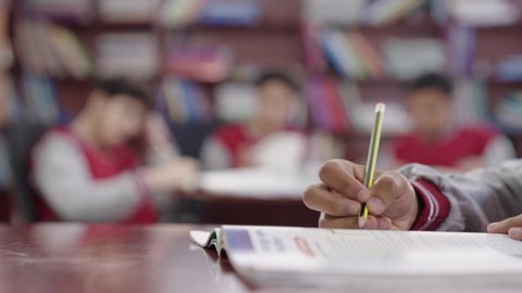 Studying for school exams, completing school assignments, reviewing lessons, preparing for the new school year, education in Saudi Arabia, back to school, a close-up shot of the hand of a Saudi Gulf Arab student solving school lessons.