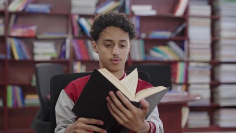 Developing reading skills for students, love of culture and exploration, visiting the school library, a close-up shot of a Saudi Gulf Arab student wearing a school uniform holding a book, education and study in Saudi Arabia, spending free time learning and self-cultivation.