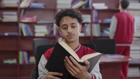 حب الثقافة والاستطلاع، زيارة مكتبة المدرسة، تصوير مقرب لطالب عربي خليجي سعودي يرتدي الزي المدرسي يحمل بيده كتاب، تنمية مهارة القراءة للطلاب، التعليم والدراسة في السعودية ، قضاء وقت الفراغ بالتعلم والتثقف الذاتي