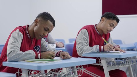 End-of-semester exams, education and curricula for students in the Kingdom of Saudi Arabia, a group of Arab Gulf Saudi students wearing school uniforms are solving exam questions, gestures of contemplation and focus.