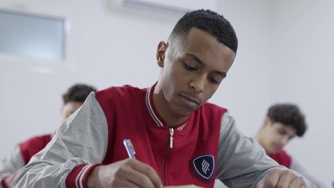 تطوير المناهج التعليمية، التربية والتعليم بالمناهج المقررة للطلاب في المملكة العربية السعودية، مفهوم الاجتهاد والتفوق, مجموعه من الطلاب العربيون الخليجيون السعوديون يرتدون الزي المدرسي يقومون بحل اسئلة الامتحان، ايماءات التمعن و التركيز