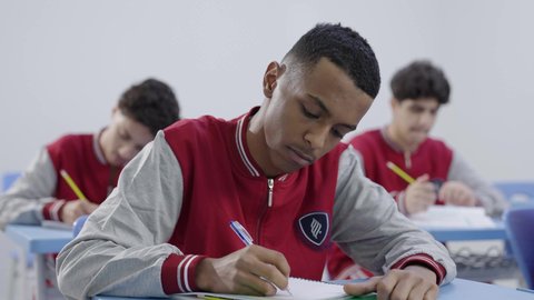 Education and teaching with the prescribed curricula for students in the Kingdom of Saudi Arabia, the concept of diligence and excellence, a group of Arab Gulf Saudi students wearing school uniforms solving exam questions, gestures of contemplation and focus.