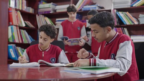 A developed educational school environment, the concept of self-learning, innovative schools in the Kingdom, a group of Arab Gulf Saudi students sitting in the school library, enjoying reading books, academic schools in the Kingdom of Saudi Arabia, doing homework.