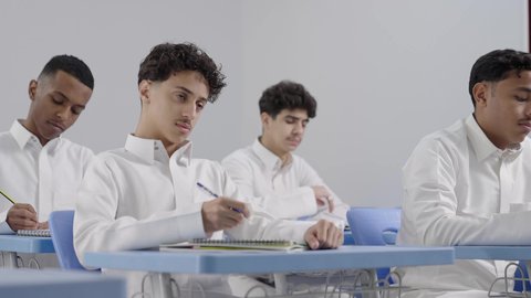كتابة و تدوين الملاحظات، أهداف التربية والتعليم بالمناهج المقررة للطلاب والطالبات في السعودية، تصوير مقرب لمجموعه من الطلاب العربيون الخليجيون السعوديون يقومون بالاستماع شرح الدرس داخل الفصل المدرسي
